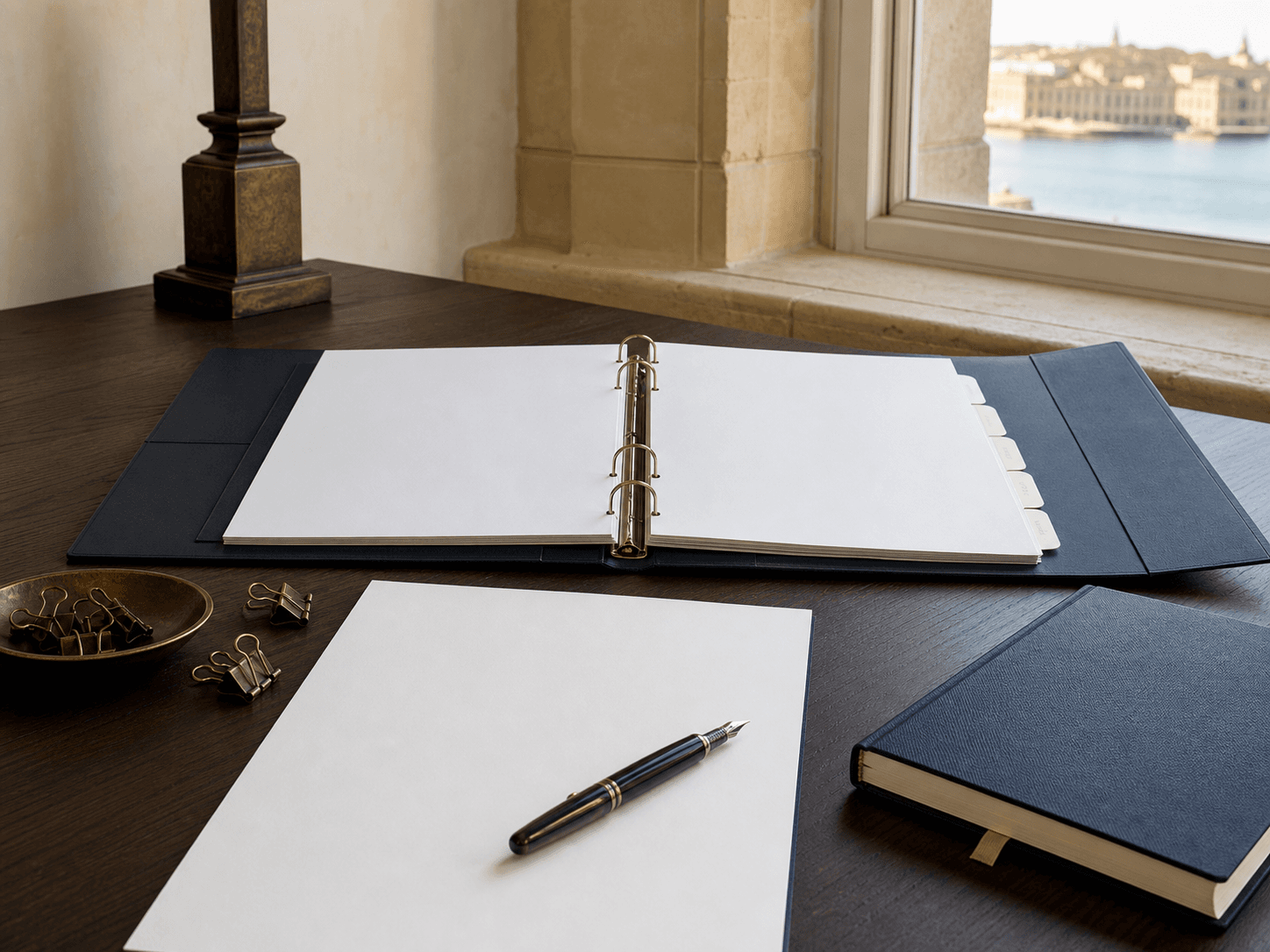 Blank policy binder, review papers and compliance ledger on a Malta office desk